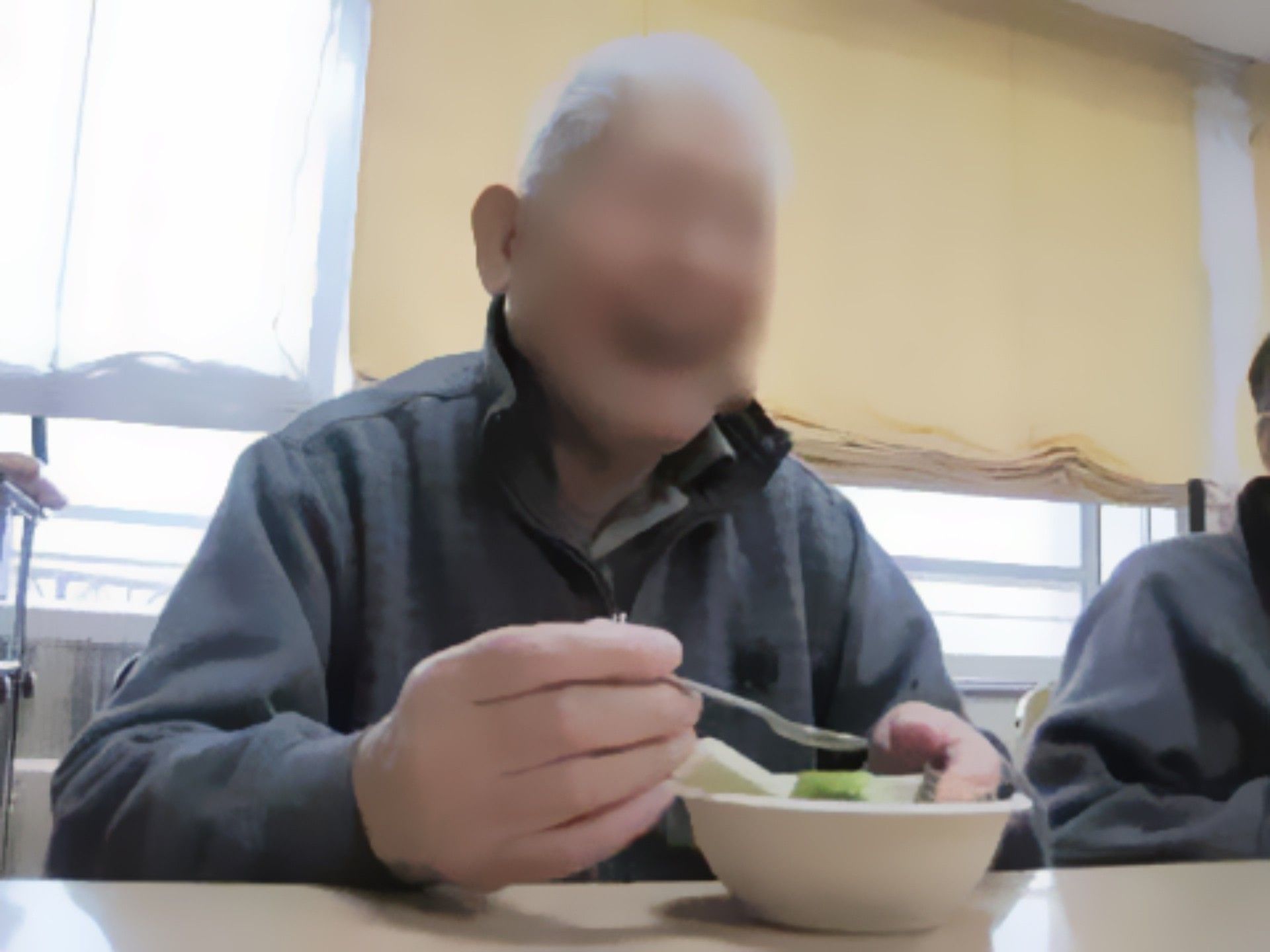 盛り付けられた食事を、スプーンを片手に笑顔で楽しむ入居者様の男性