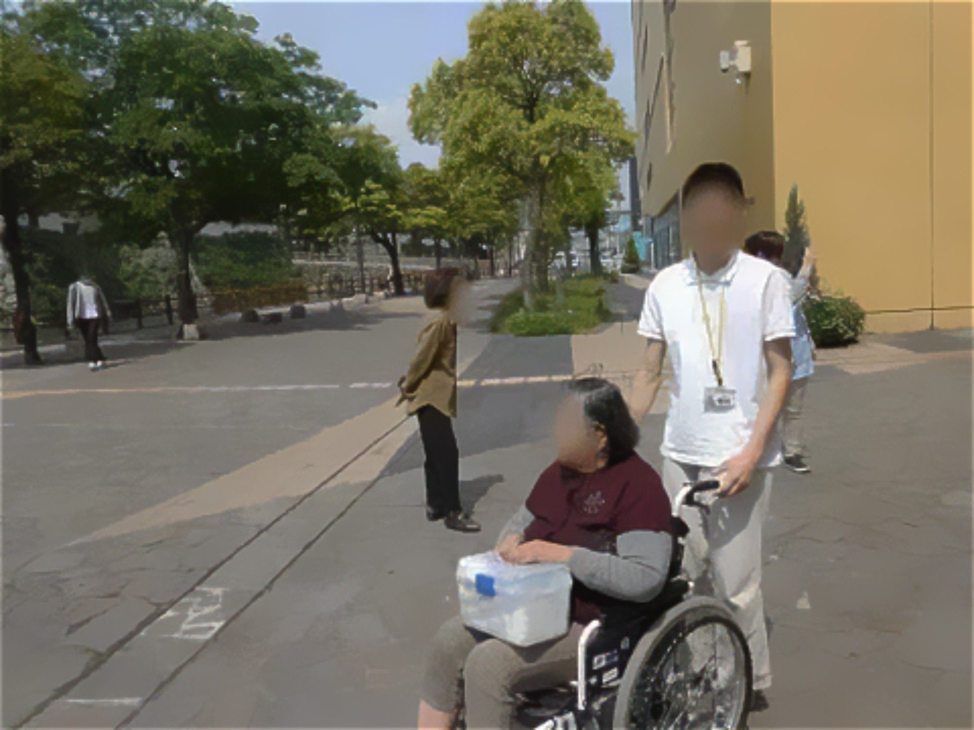 男性スタッフに車椅子を押してもらいながら、散歩をする入居者の女性