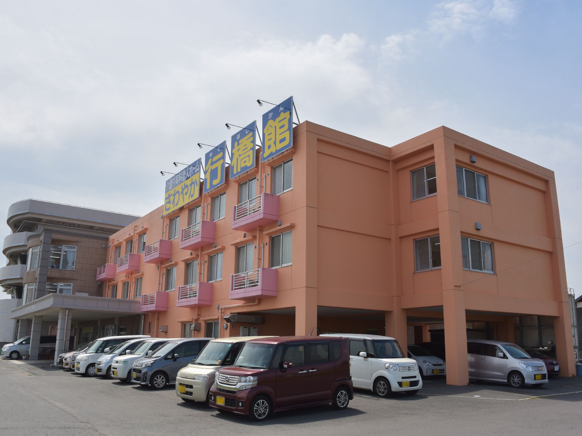 3階建ての建物で、壁の色が鮮やかなピンク色になっているので、一目で施設が分かる。駐車場も完備されている。