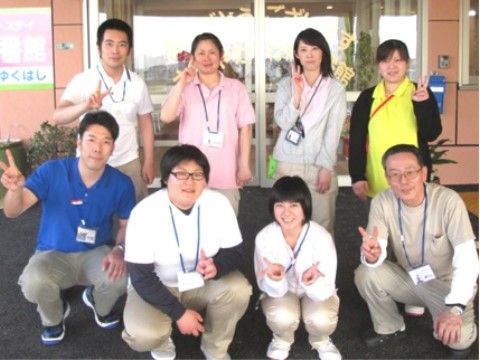 名札フォルダーを首から下げ、二列に並んで笑顔でポーズをとるスタッフたち