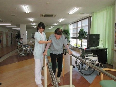スタッフに支えられながら、歩行補助器具でリハビリを行う入居者様