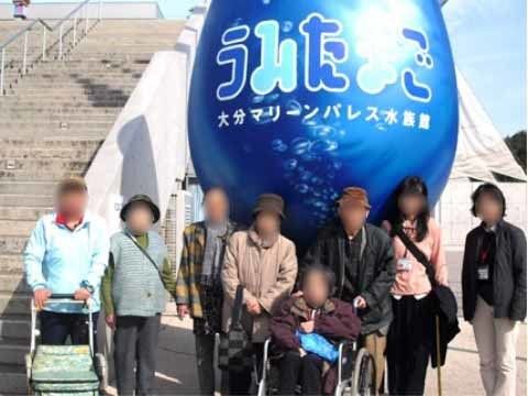 水族館の大きなオブジェ前で並んでいる、8名の入居者様たち