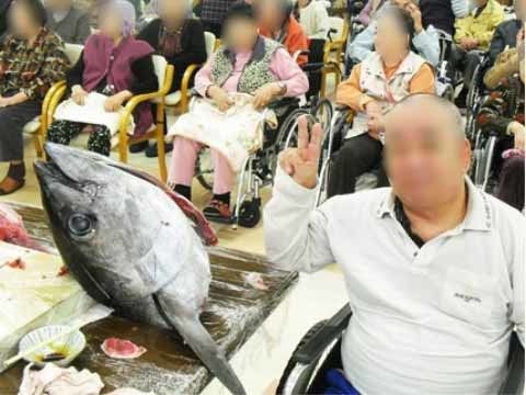 大きなマグロのお頭の横で、ピースをしている男性入居者様