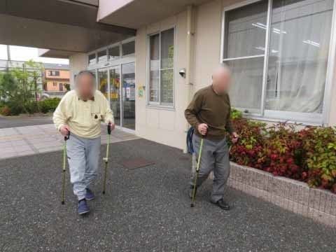 施設の建物前で、両手に杖を持って歩く二名の男性入居者様