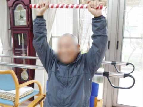 紅白のポールを両手で持って、ストレッチをしている男性入居者様