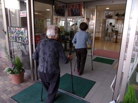 杖を突きながら施設の玄関に入っていく、二名の女性入居者様