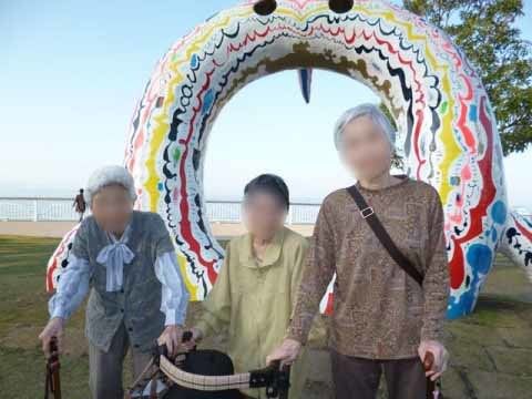 海辺に置かれた円形のオブジェの前で並んでいる、3名の女性入居者様