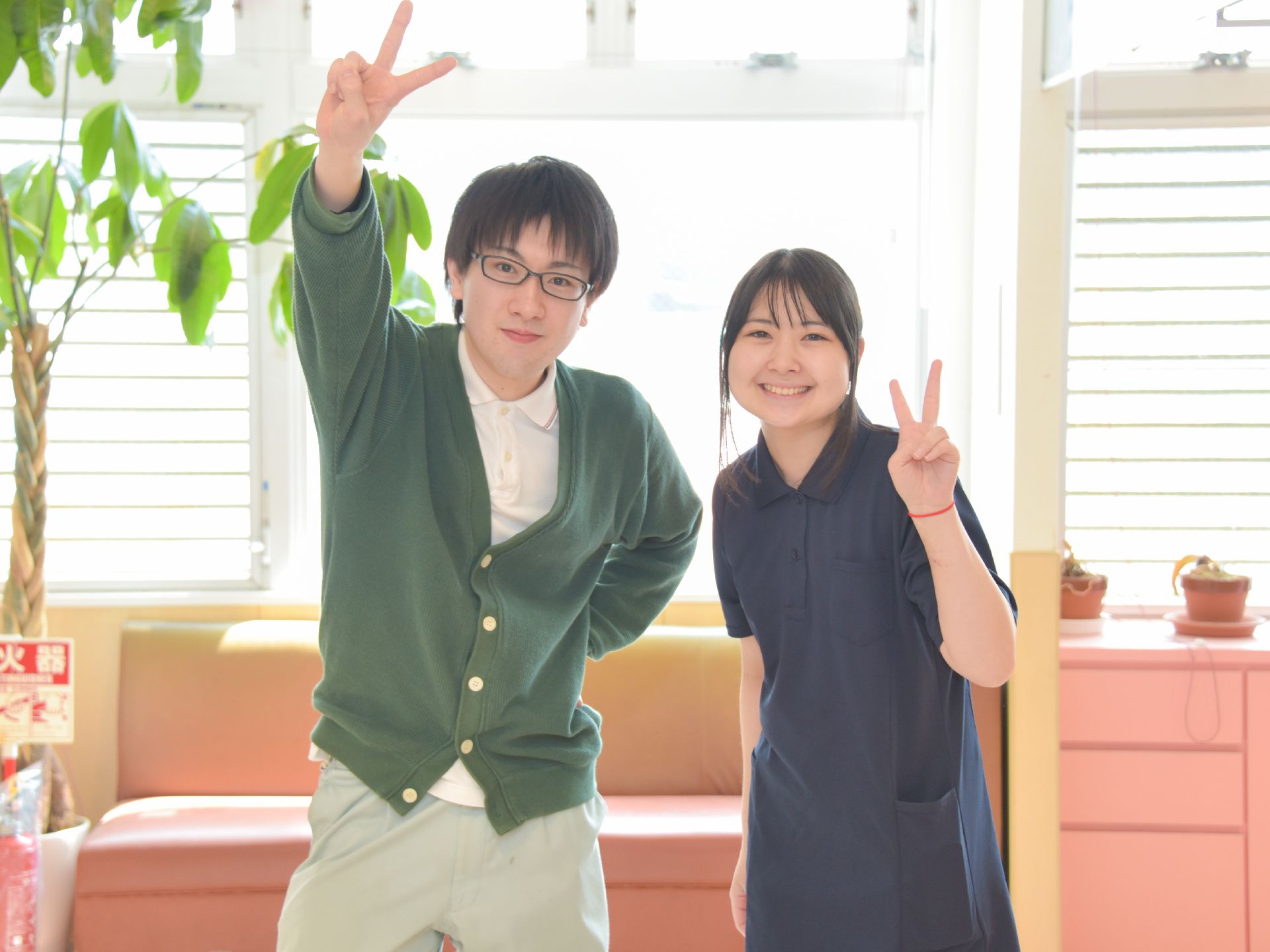 施設スタッフの写真。深緑のカーディガンを着た眼鏡の男性と、紺色のエリつきシャツを着た女性スタッフ2人。