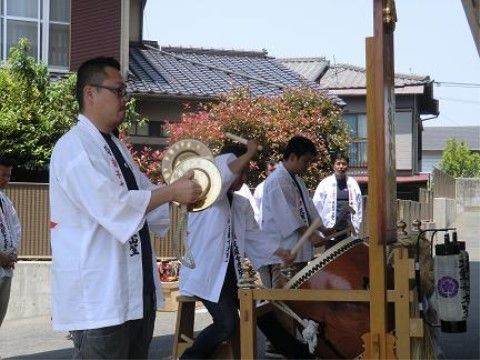 太鼓や小さなシンバルを使い、楽器の演奏をしている白い法被姿の男性たち