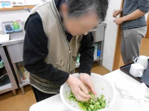 キッチンに立って、きゅうりの塩もみをしている入居者の女性