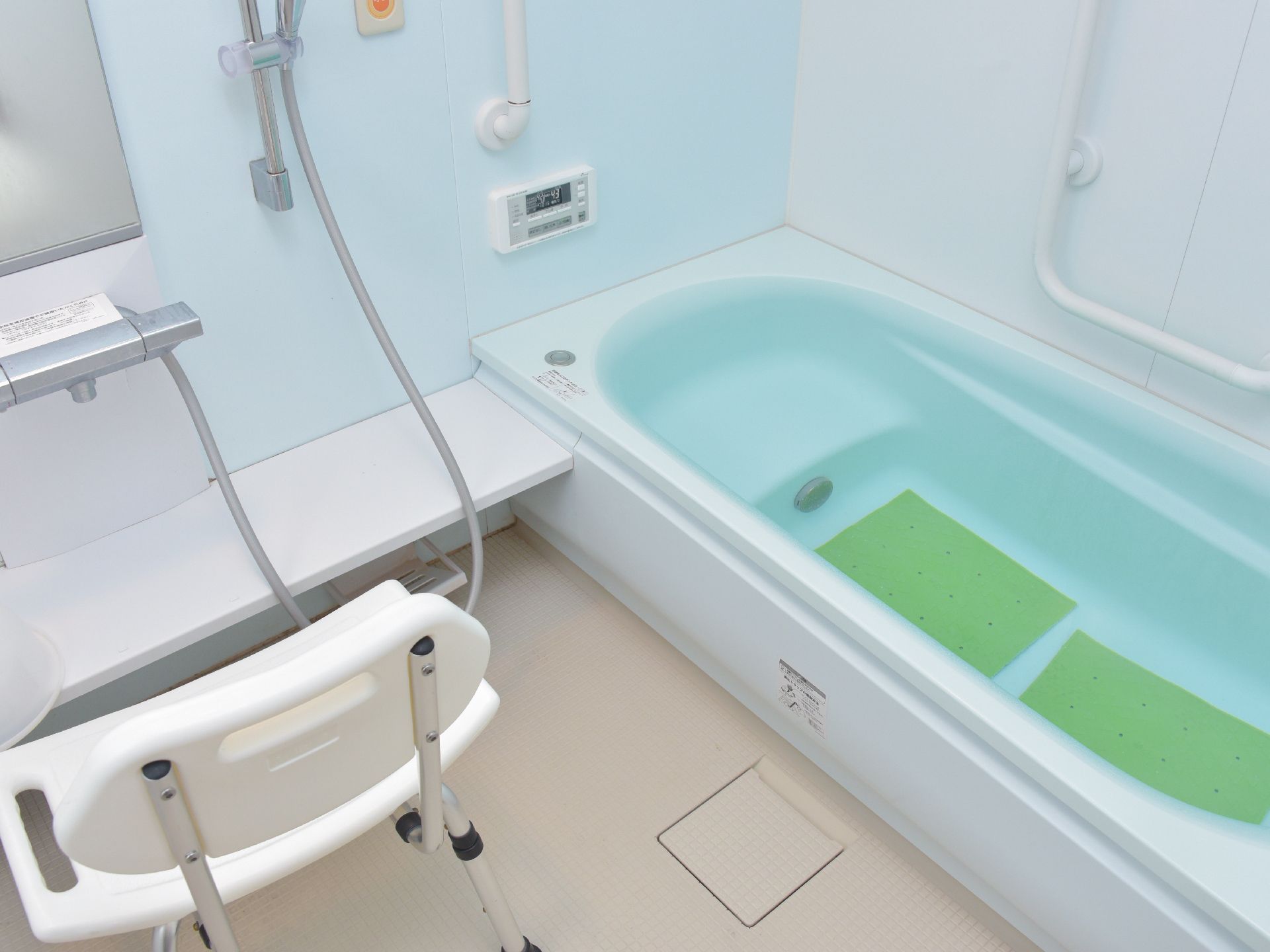 お風呂は、水色の湯船が特徴的なデザインをしている。お風呂用の椅子が置かれているので、安心して利用できる。