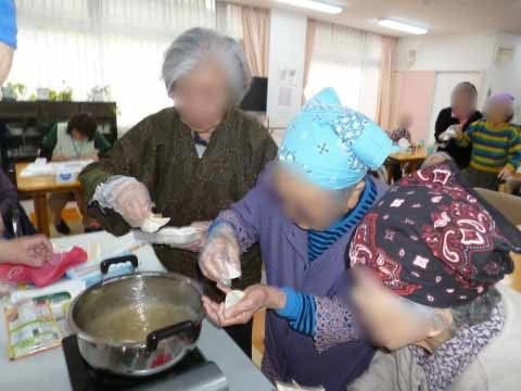 鍋に火をかけ、頭にスカーフを巻いて調理をしている入居者の女性たち