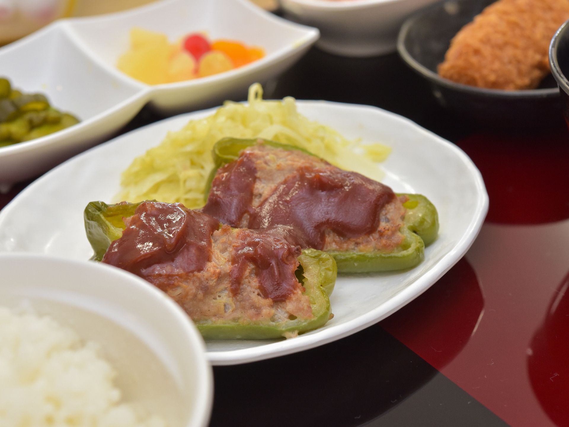 キャベツが添えられて、白い器に盛りつけられているピーマンの肉詰め