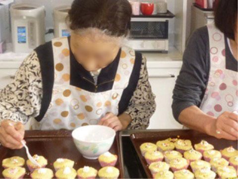 エプロンを着て、キッチンで調理の手伝いをしている女性入居者様