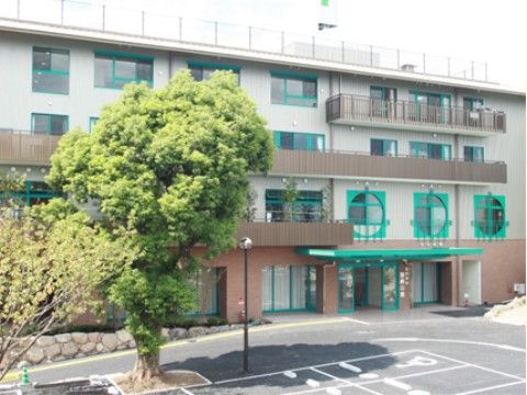 広い敷地に建つ３階建ての施設である。駐車場に背の高い大きな木が植えられている。車椅子専用の駐車場もある。