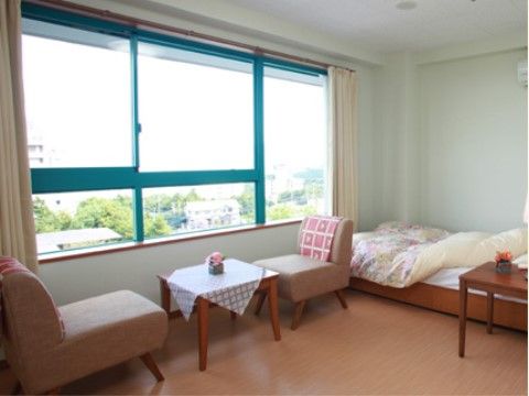 大きな窓が設置されており、椅子に座って外の風景が眺められる。テーブルには小さな花が飾られ、おしゃれな雰囲気。