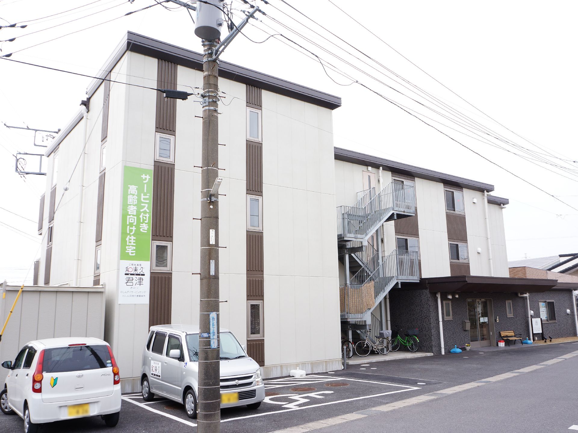 建物の前に数台分の駐車スペースがある、白い外壁の施設外観