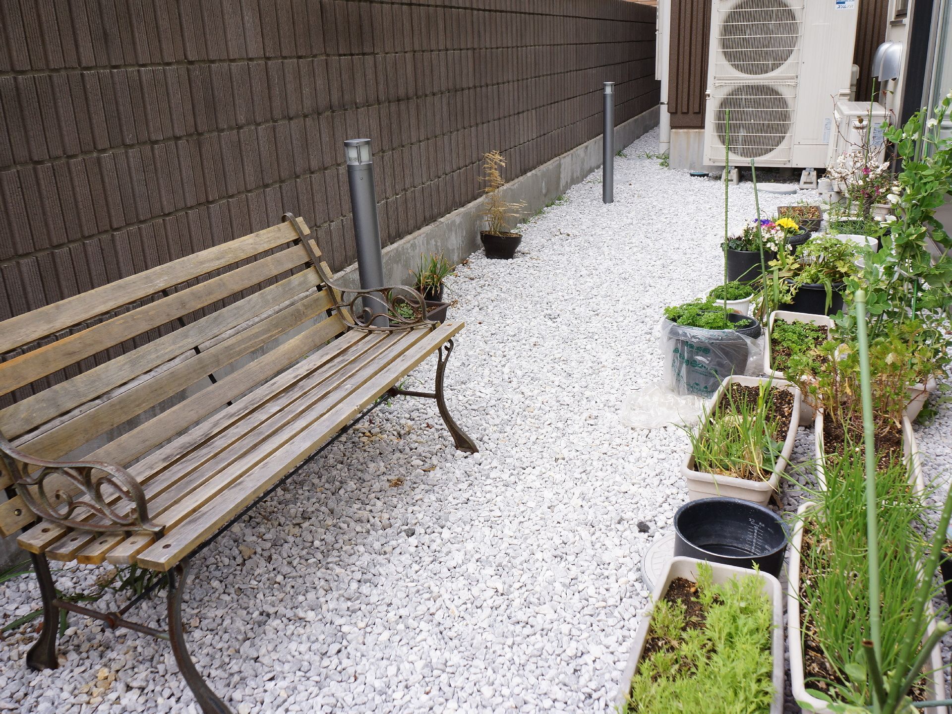 建物周辺のフリースペースにはベンチやプランターがある。ネギなどの野菜や花が植えられている。外灯があるので夜間の外出もできる。