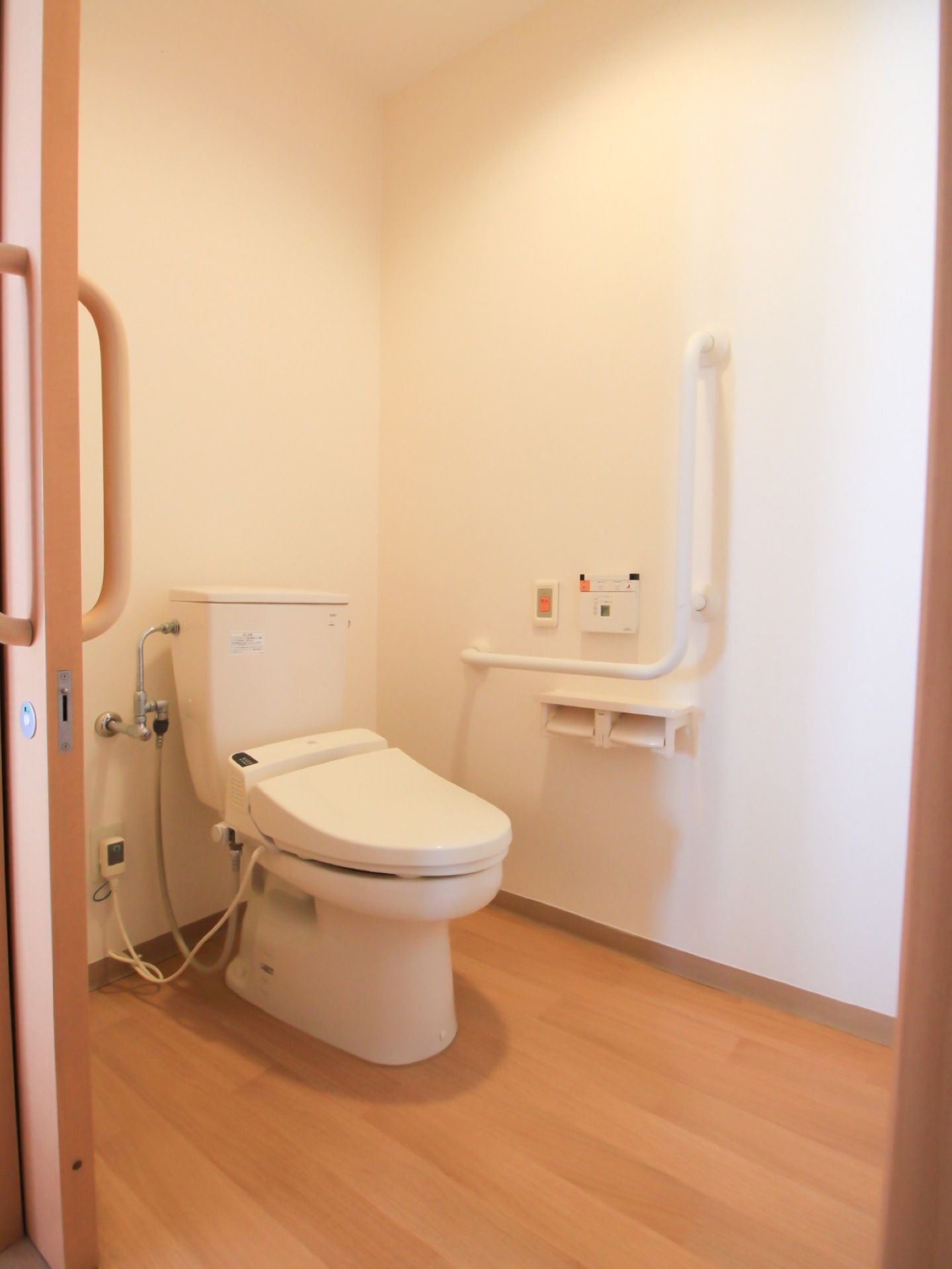 居室に設置されているトイレは、ドアが引き戸で段差がなく清潔な造りとなっている。壁には手すりや操作ボタン、ナースコールなどが設置されている。