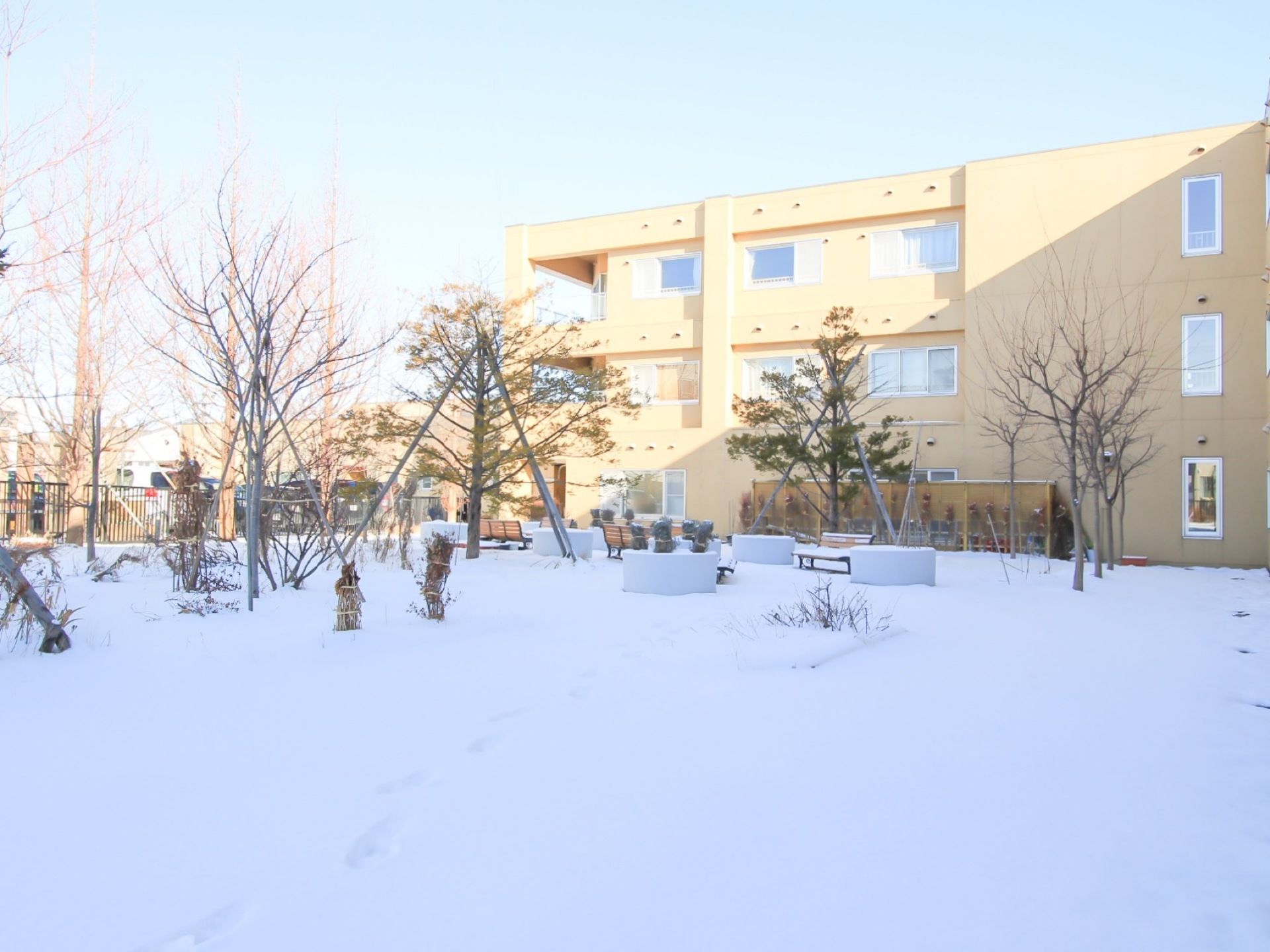 施設はオレンジ色の３階建ての建物で、敷地内には広い中庭が設けられている。複数の木々が立ち並び、ベンチが設けられている。