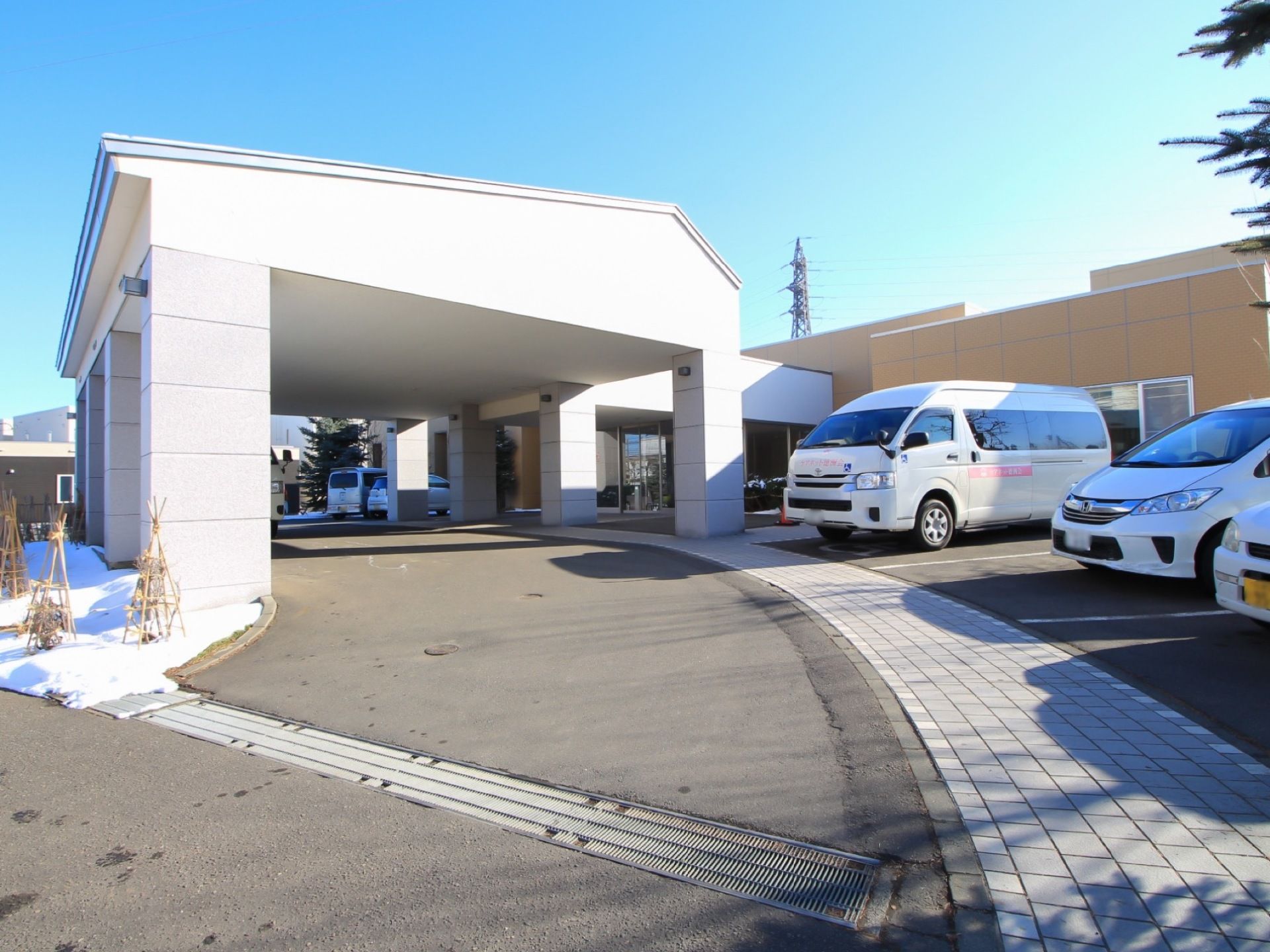 玄関前には通路があり、車が直付けできるようになっている。通路の上には白色のしっかりとした柱で支えられた大きなひさしが設置されている。