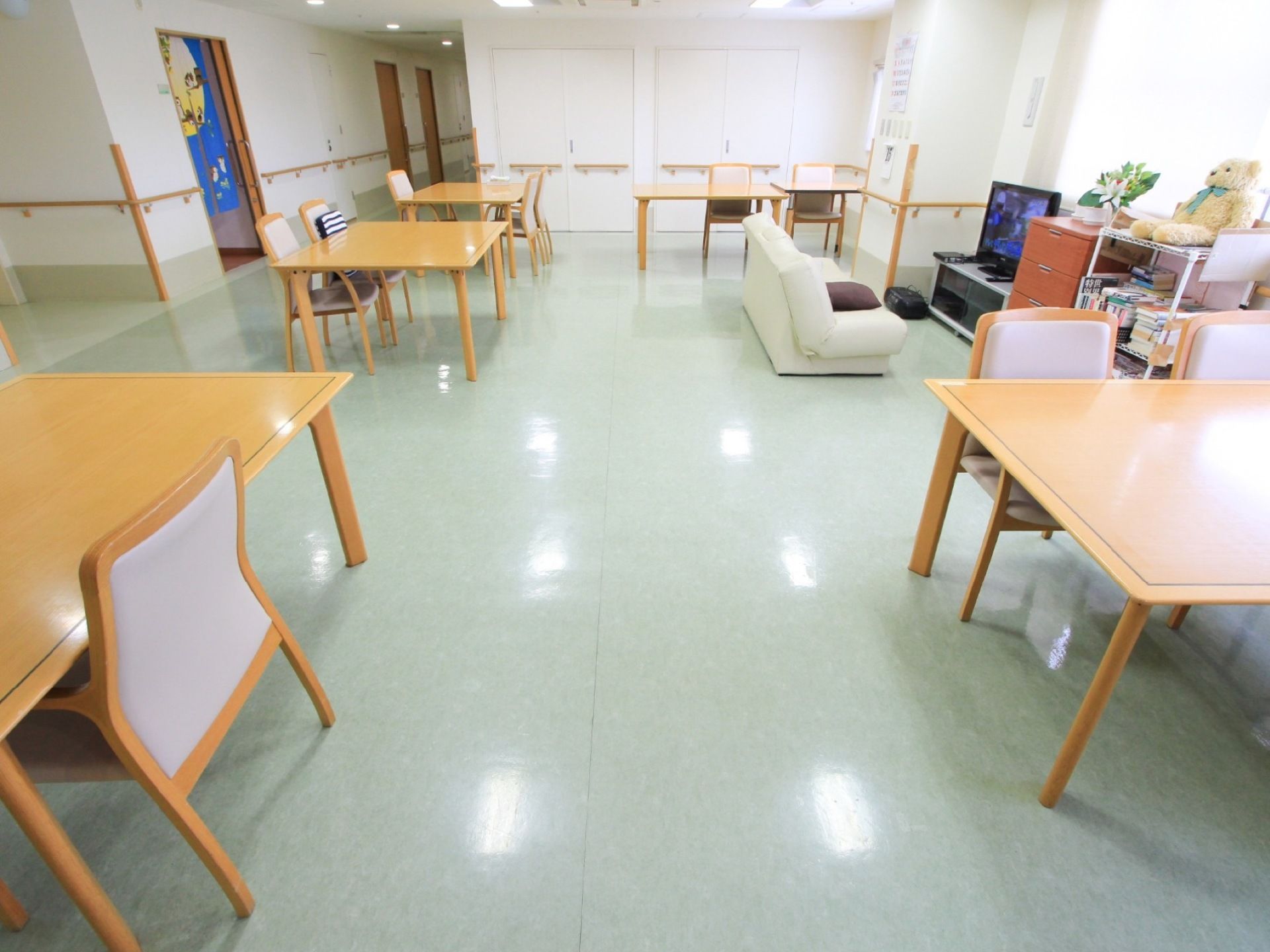 ピカピカに磨かれた薄い色の床の部屋にテーブルや椅子が置いてある。白いソファーの正面にはテレビボードに乗せられたテレビがある。
