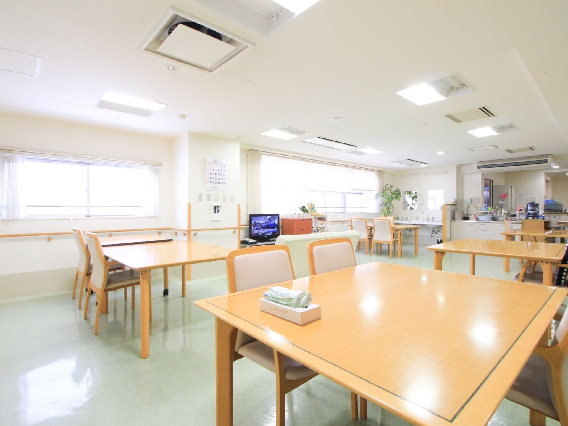 窓から入る光と天井に設置された照明の光で室内はとても明るい。数台のダイニングテーブルや椅子が置いてある。