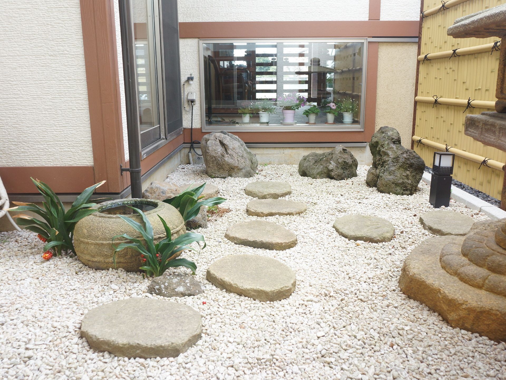 小さなスペースを生かした和風庭園風の中庭。季節を問わない情緒。味わいのある形の岩の向こうには正面玄関の足元が見える。