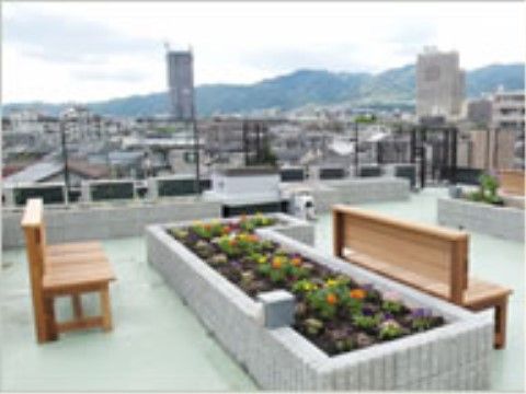 「サンライフ住吉川」の屋上テラス。花壇には花々が植えられており、ベンチに腰掛けることができる。