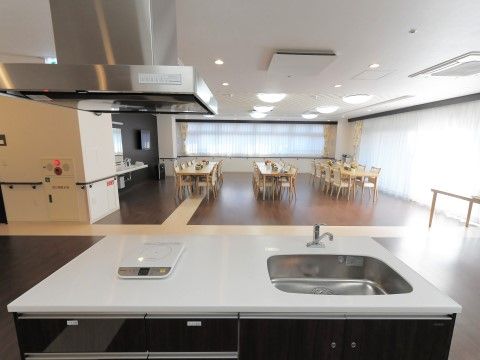 奥には空間の広い食堂があり、長テーブルが置かれている。その一角にアイランドキッチンが備えられている。