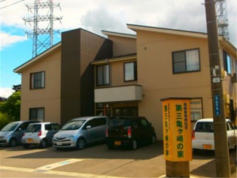 建物前に数台の車が駐車している、一軒家風の施設外観