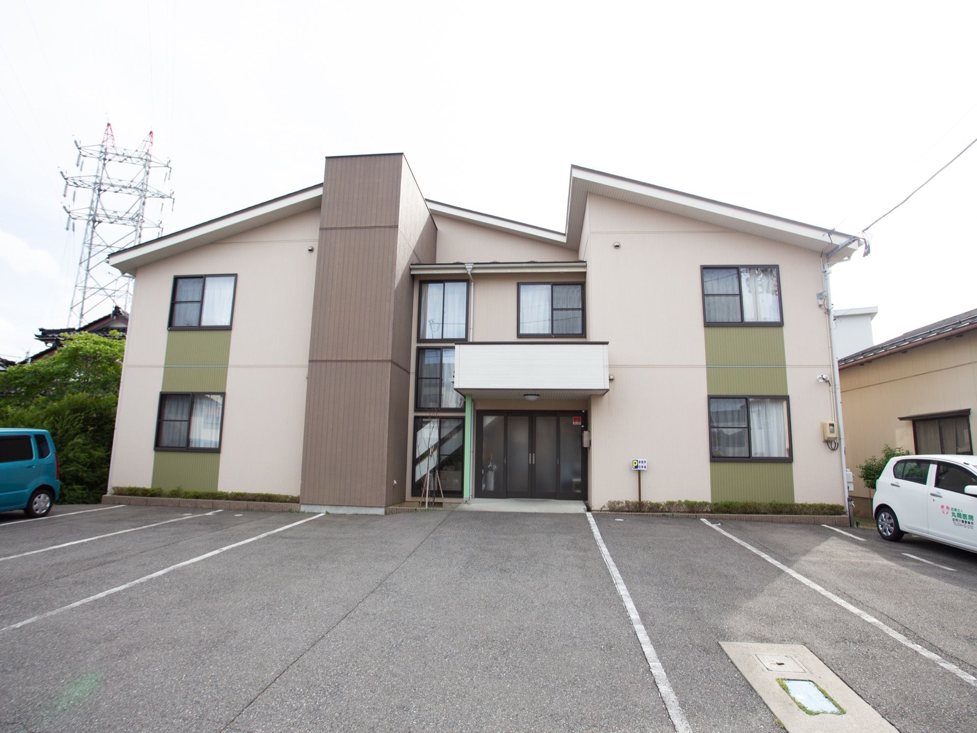 玄関を中心に左右に広がった構造の２階建ての施設である。建物の前の広い敷地に、長い白線が描かれている。