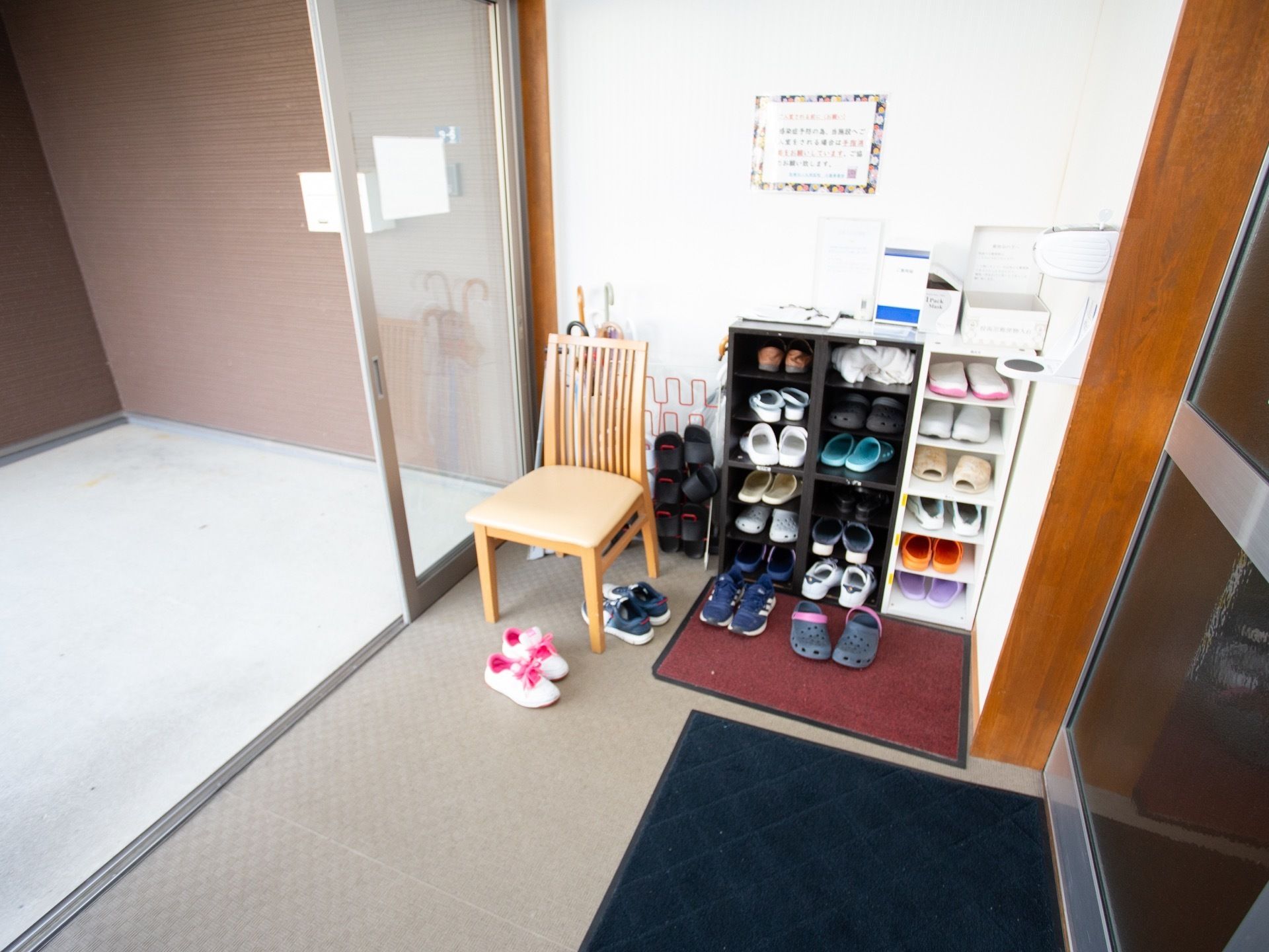 玄関扉は自動扉になっており、床には玄関マットが敷かれている。下駄箱にはサンダルや靴が収納されている。