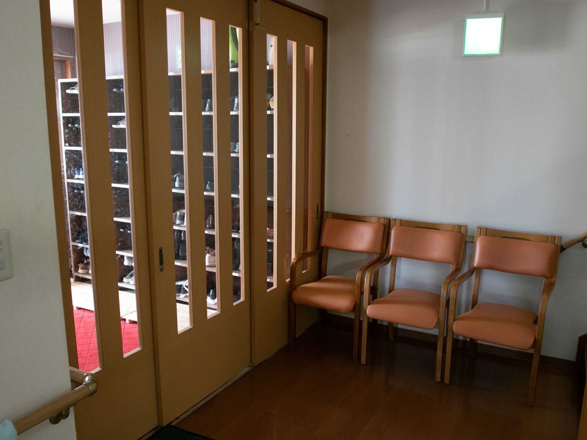 引き戸で仕切られた玄関がある。ホーム内はフローリングで、壁際には椅子が３脚置かれている。壁には手すりが付いている。