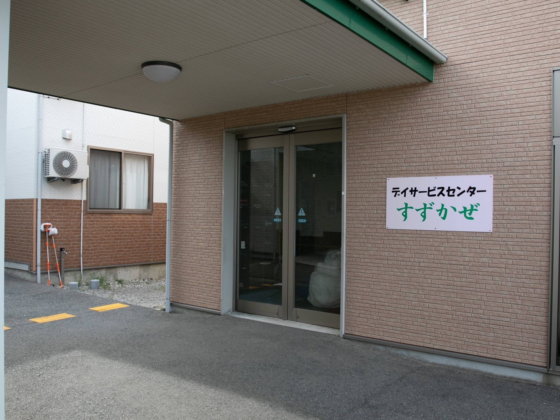 デイサービスセンターの入り口がある。両開きの自動ドアで、前には屋根があり、車が寄せられるスペースがつくられている。