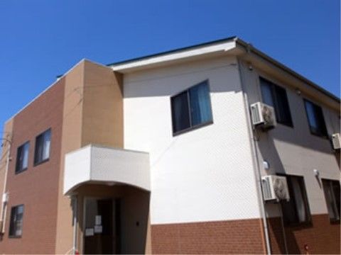 青空に映える、一軒家のような造りをした二階建て施設外観