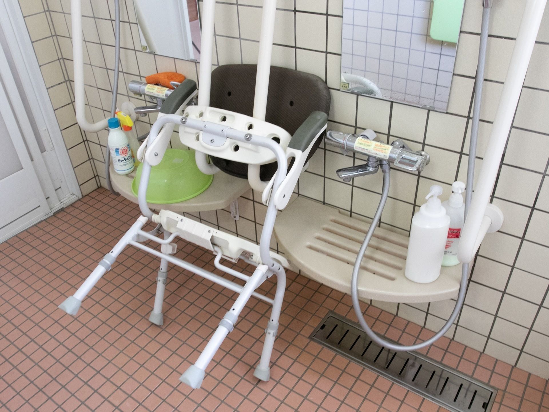 洗髪コーナーには、椅子が壁に立て掛けられ、小さなテーブルの上にシャンプーボトルが置いてある。蛇口の上部には鏡、脇には手すりが付いている。