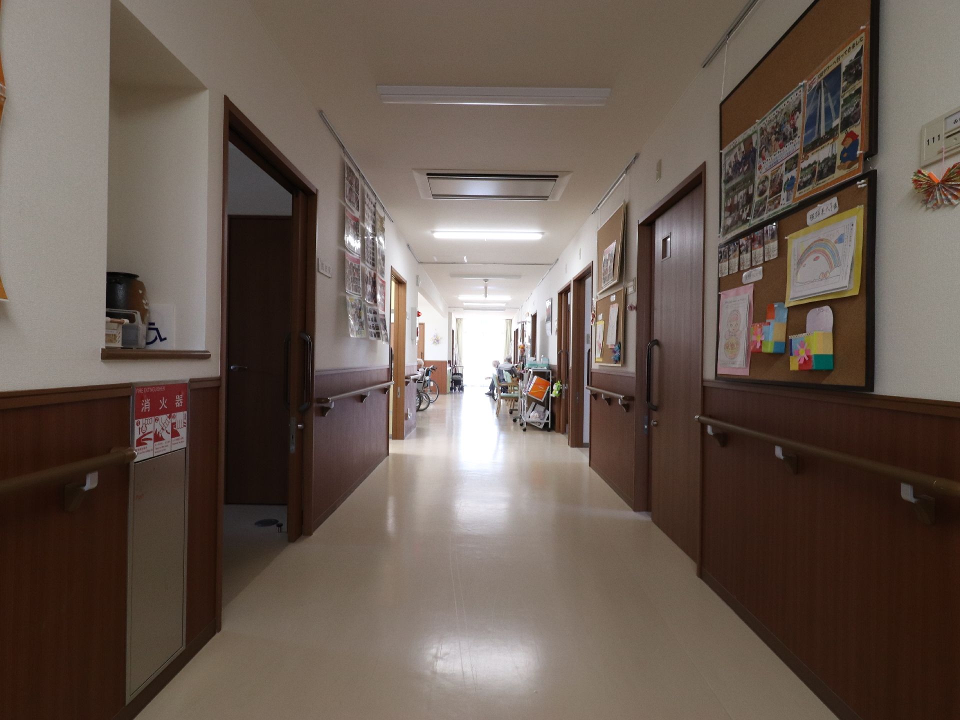 壁や個室の扉がこげ茶色で統一され、落ち着いた廊下になっている。壁には手すりが設置されリハビリの場としても最適。