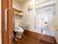 上部に収納棚が多く取りつけられた個室のトイレで、洋式便座が1台設置されている。便座の周囲に手すりが備えつけられている。