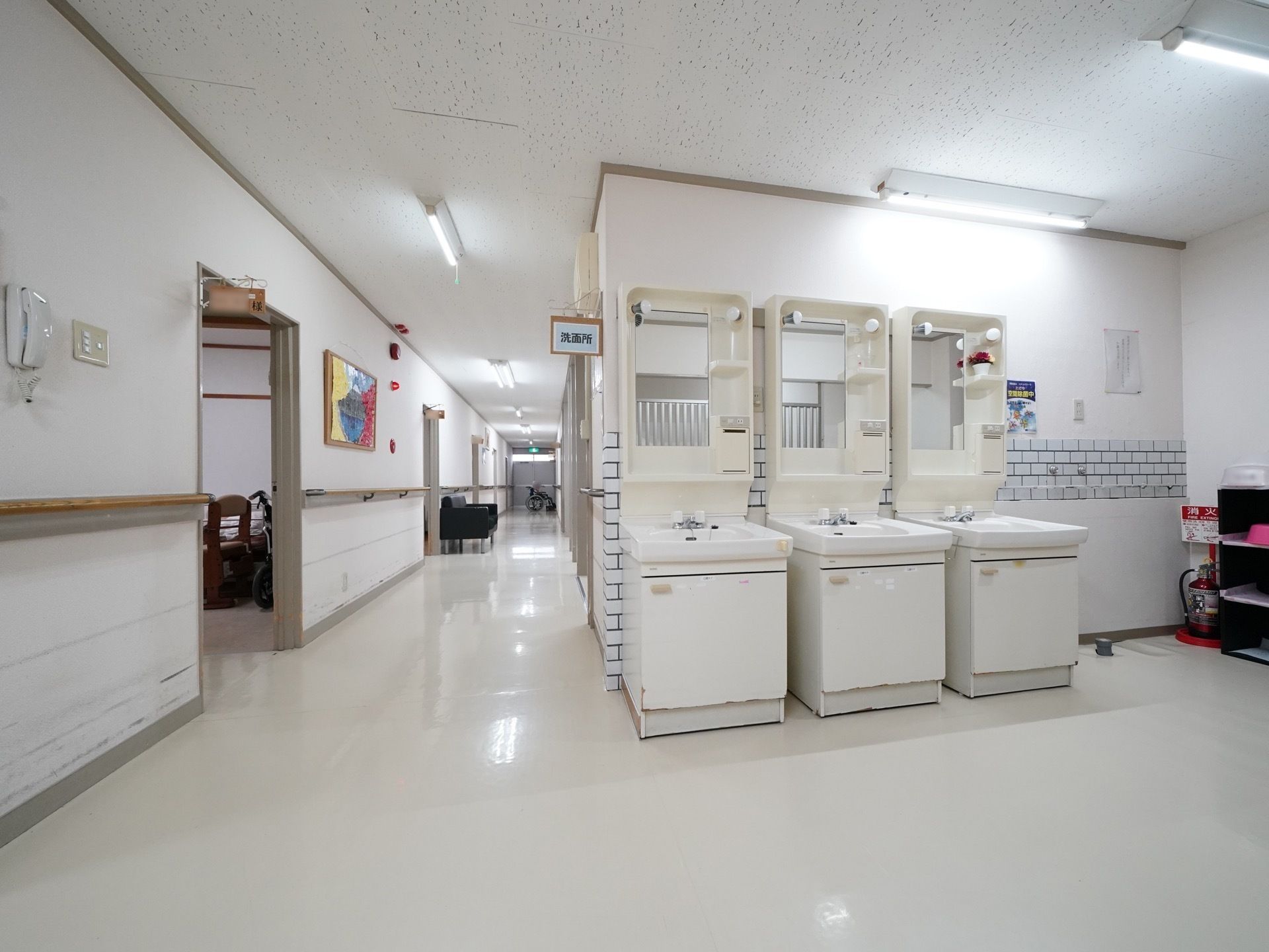 廊下の一角に洗面所の看板がついており、洗面台が３台並んで置かれている。それぞれに、照明や小物置き場、鏡が備わっている。