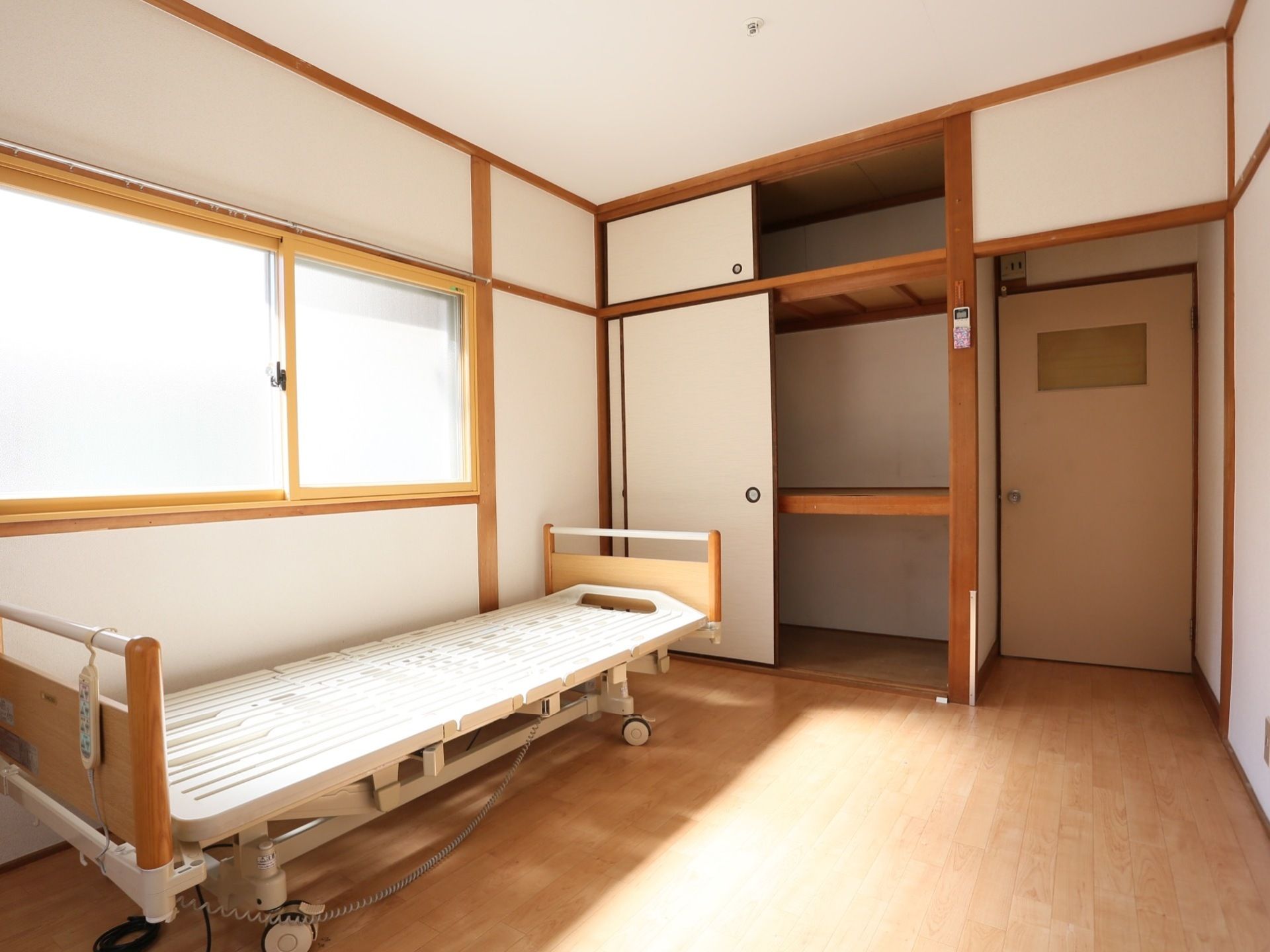板張りの和室に、電動式ベッドが置かれている。二段の押し入れの上には天袋もあり、十分な収納スペースが確保されている。