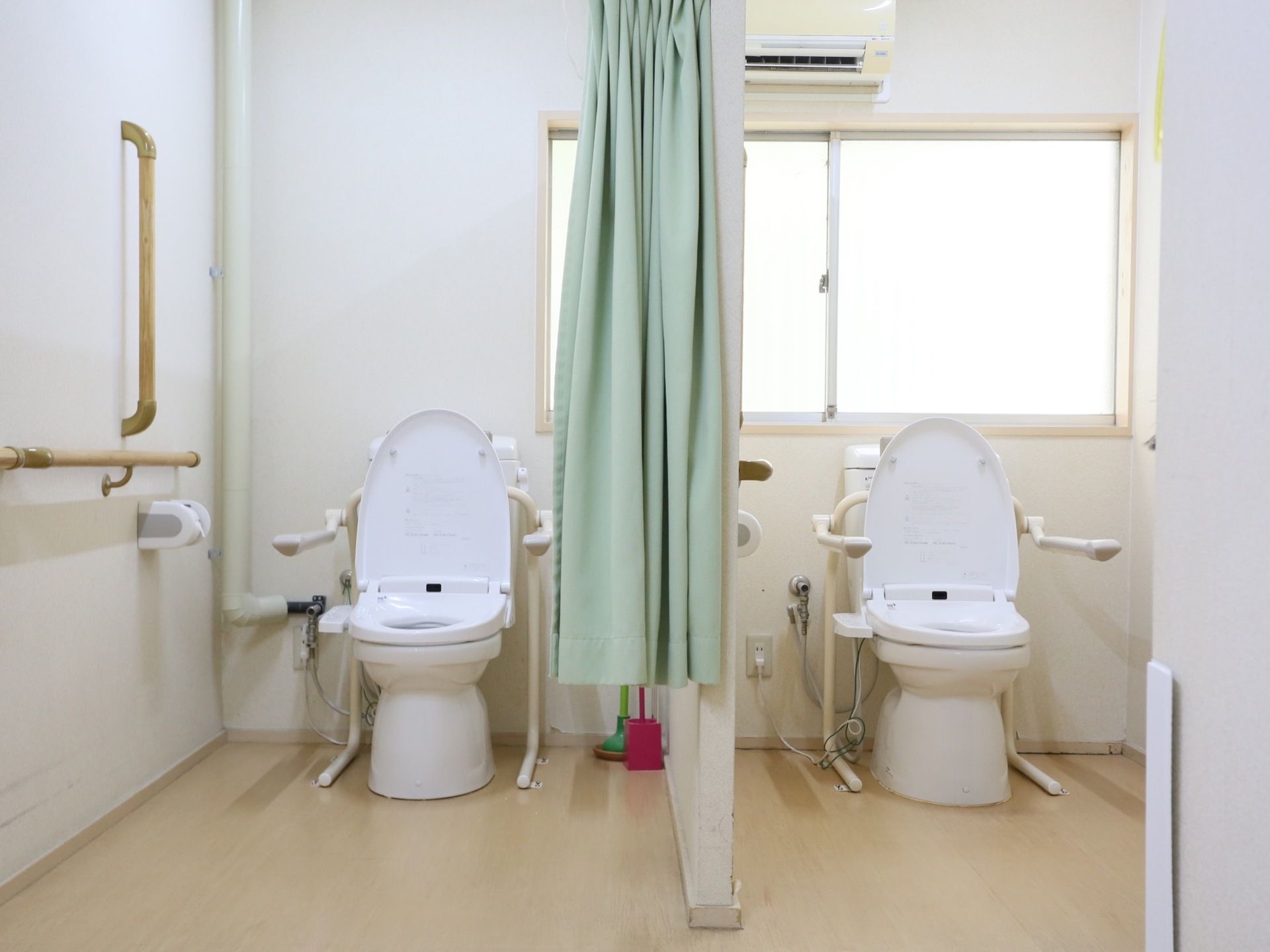 二つの洋式便所が並んでおり、カーテンで仕切られている。手すりがついており、室内にはエアコンが設備されている。