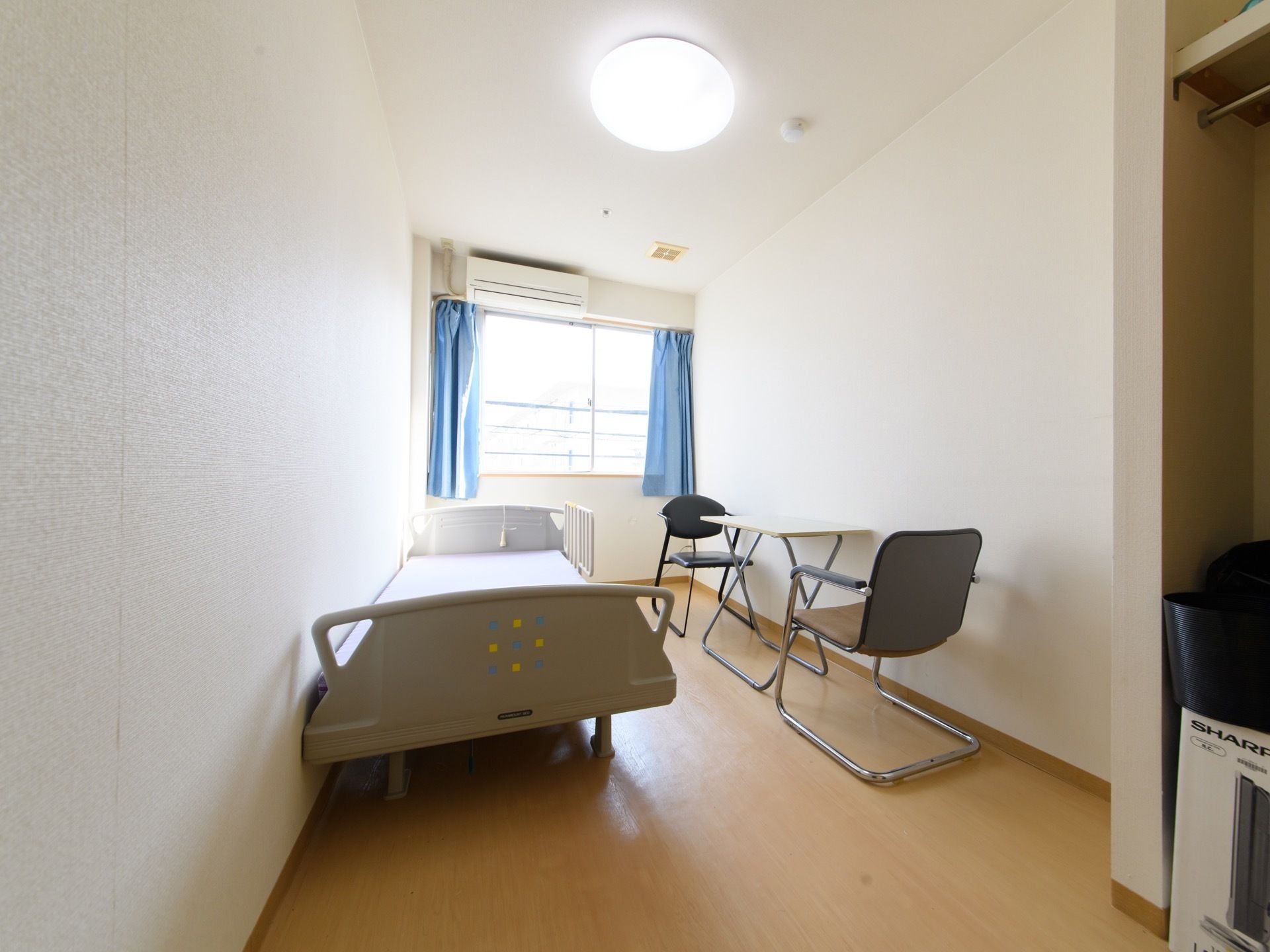 居室にはリクライニング機能がついた、介護用ベッドが置かれている。壁には窓があり、エアコンが取り付けられている。