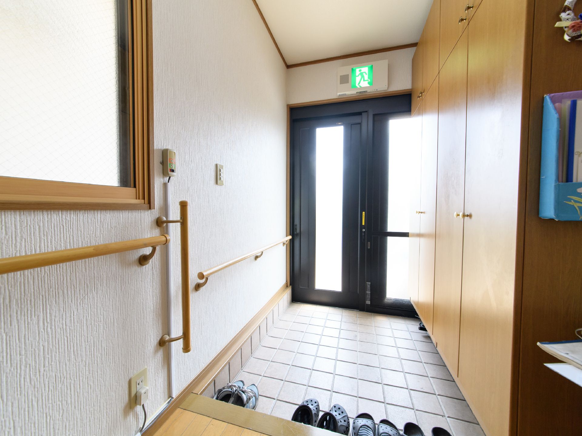 壁には手すりや緊急時呼び出しブザーが備わっている。大型の靴箱があり、たたきには靴が4足置かれている。