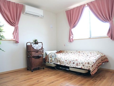 窓にはピンク色のカーテンが付いており、レースの下敷きに植物が飾られているかわいらしい居室