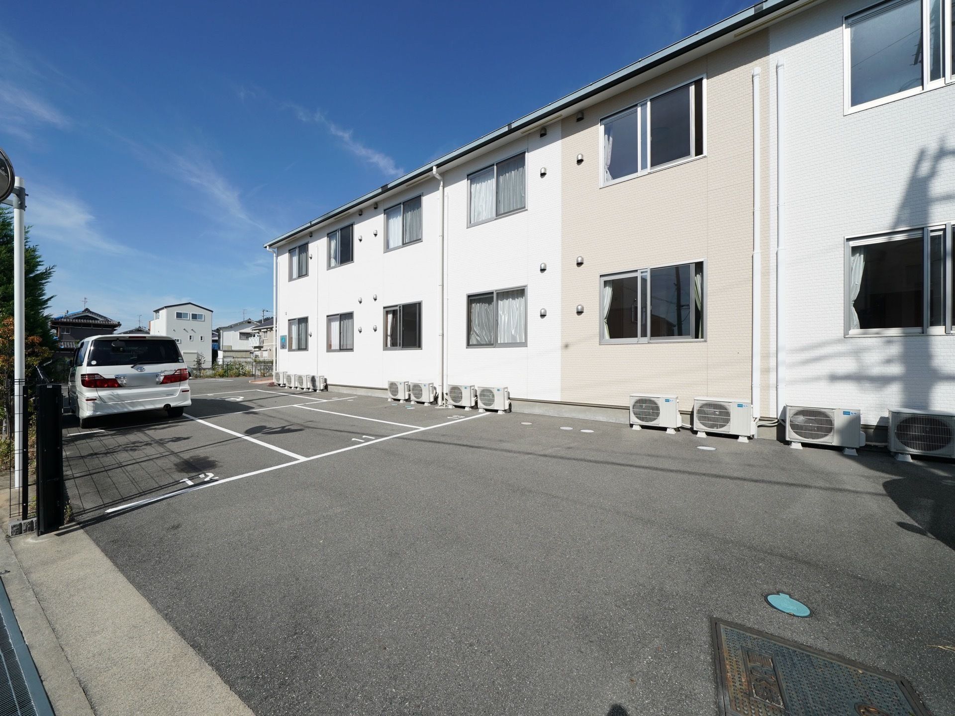 白色が基調の外壁になった２階建ての建物である。大きな駐車場を備えており、多くの車を停めることができる。