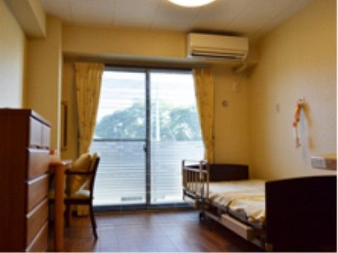 窓の近くに柵付きのベッドが設置されている、一人用の居室