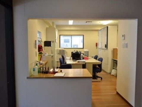 奥に事務机が向い合わせに設置されている様子が見える、受付カウンター