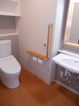 白を基調とした爽やかな雰囲気のあるトイレである。安全のための手すりやナースコールが完備されているので、１人でも不安なく利用できる。