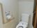居室には引き戸で仕切られた個室のトイレがある。洋式トイレのわきの壁にはＬ字型の手すりと緊急呼出ボタンが備えつけられている。